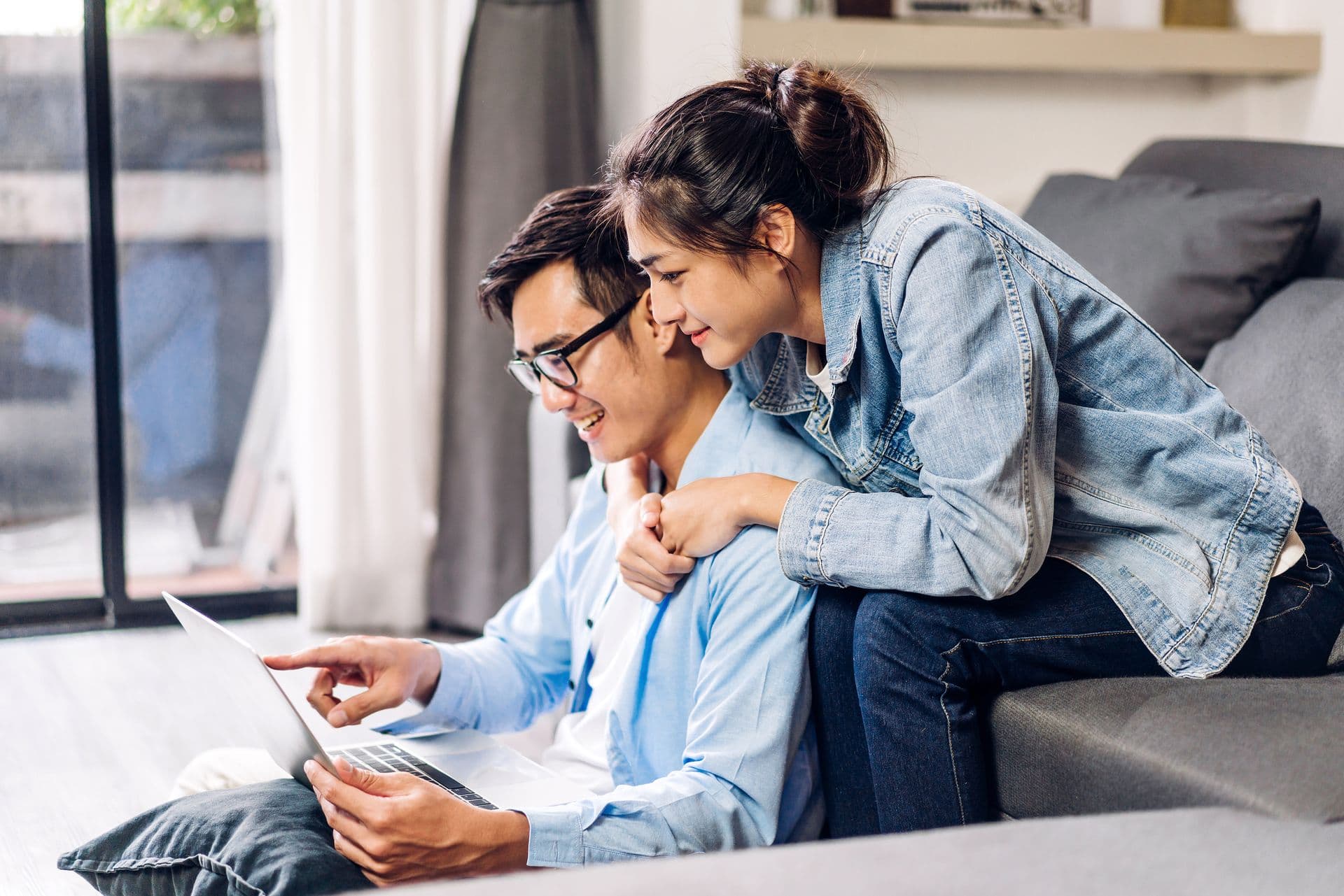 Happy couple checking social media and reading news or shopping online while sitting on at home